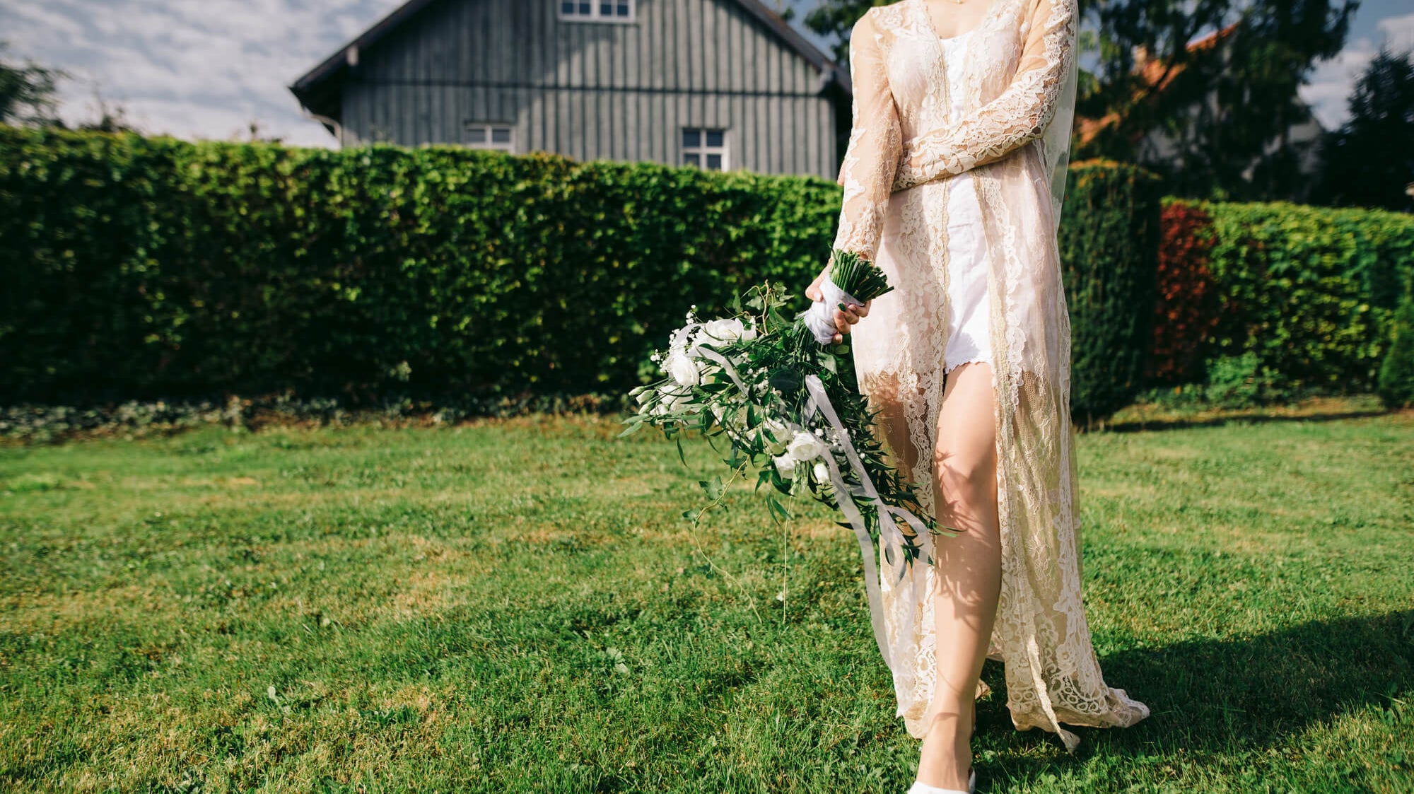 bride walking on green grass with barn in background