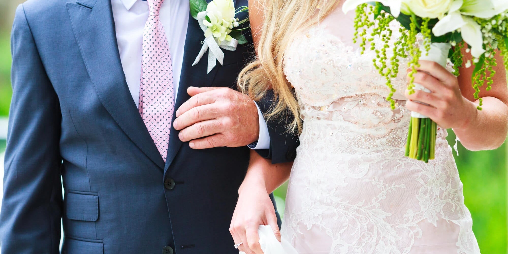 bride holding her father's arm to begin walking down the aisle while holding a bouquet of flowers