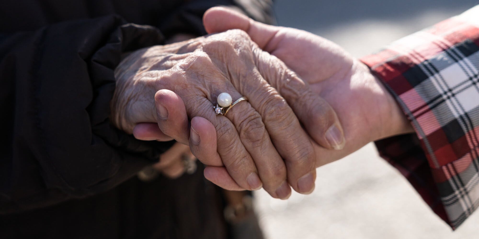 a woman holding hand with an older woman that is wearing a pearl ring