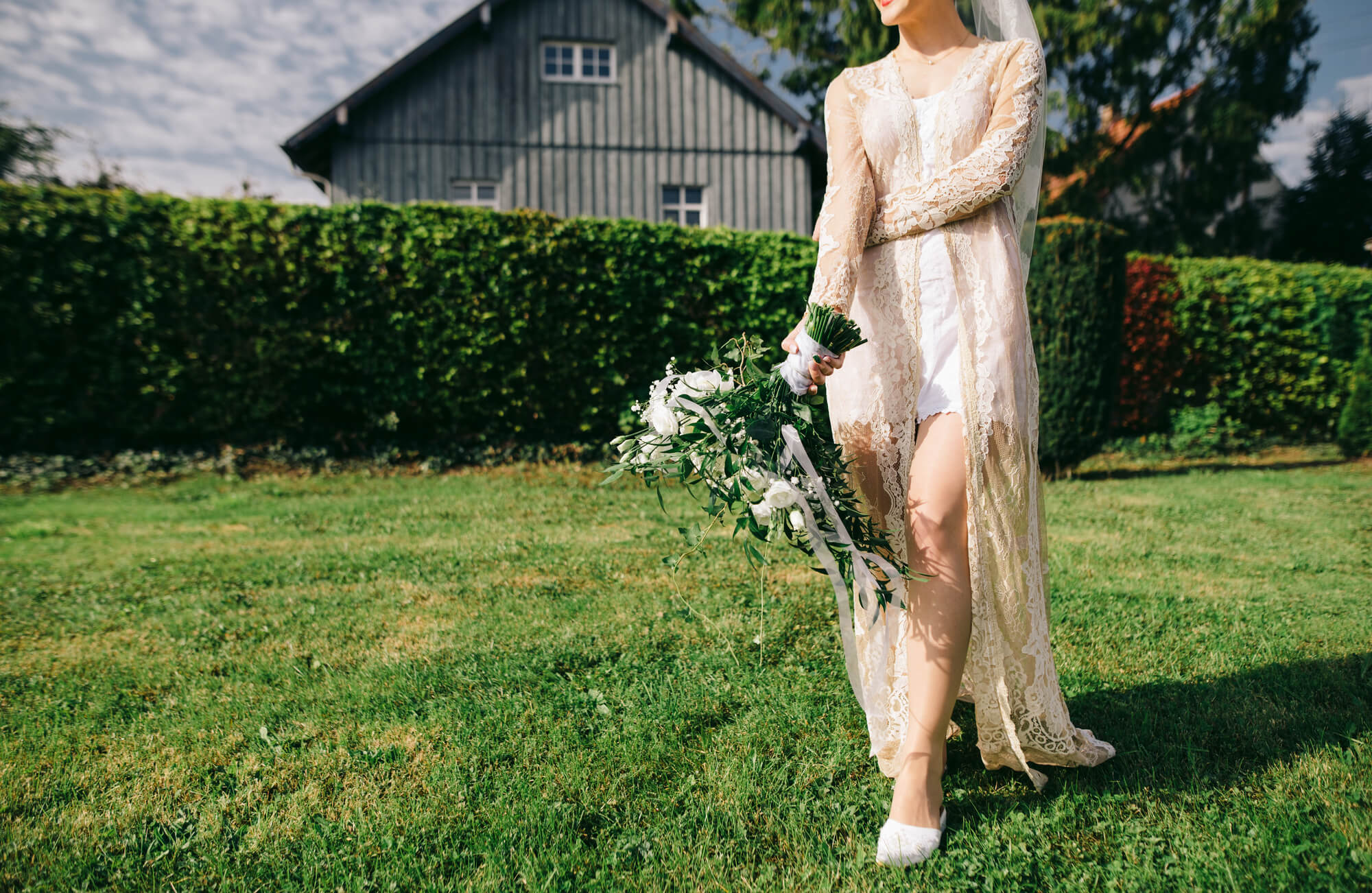 bride walking on green grass with barn in background