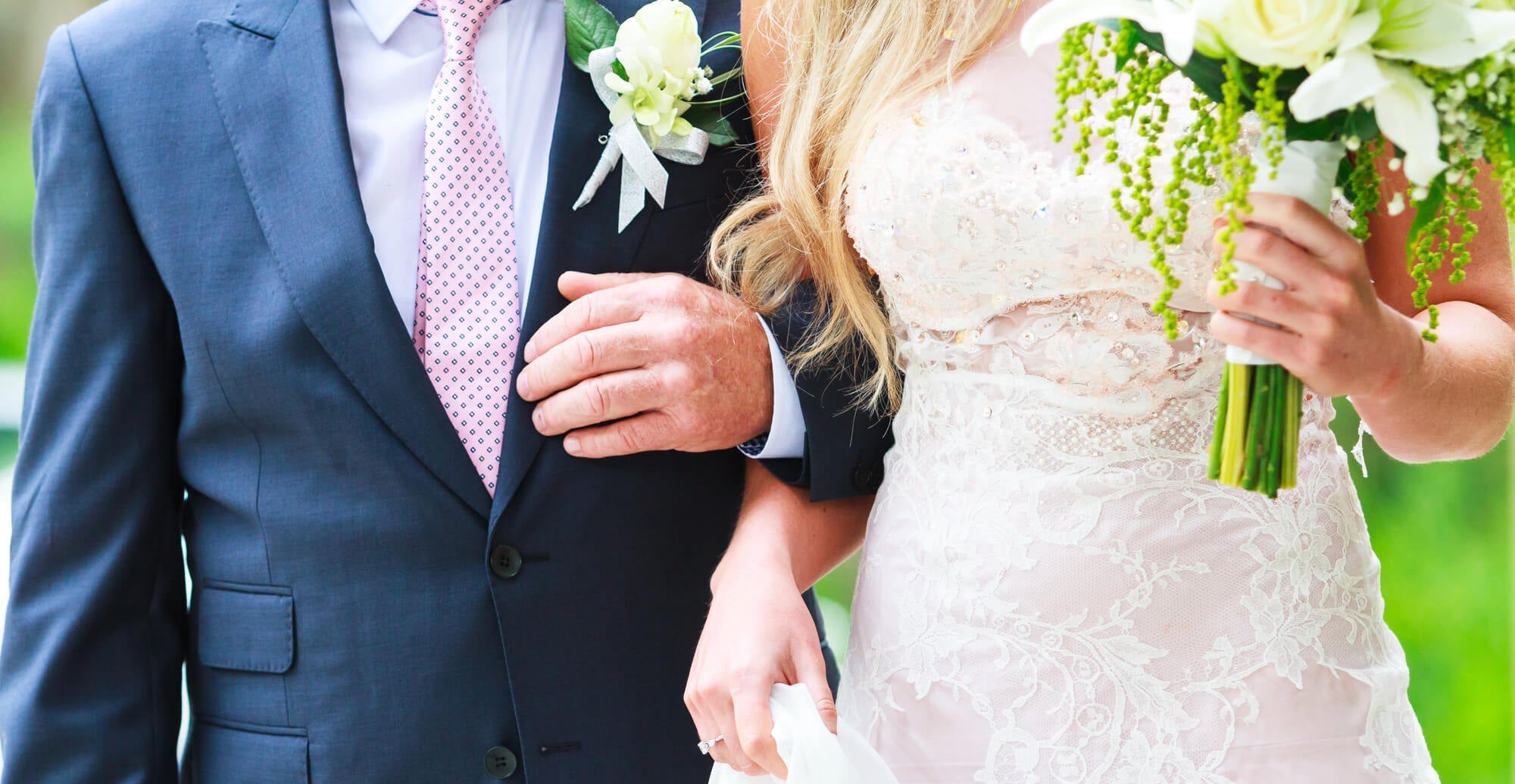 bride holding her father's arm to begin walking down the aisle while holding a bouquet of flowers