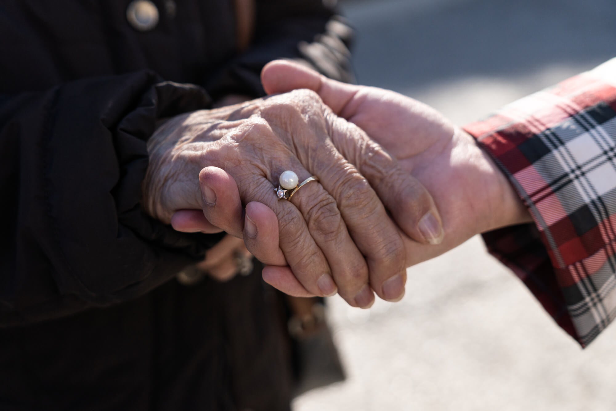 a woman holding hand with an older woman that is wearing a pearl ring