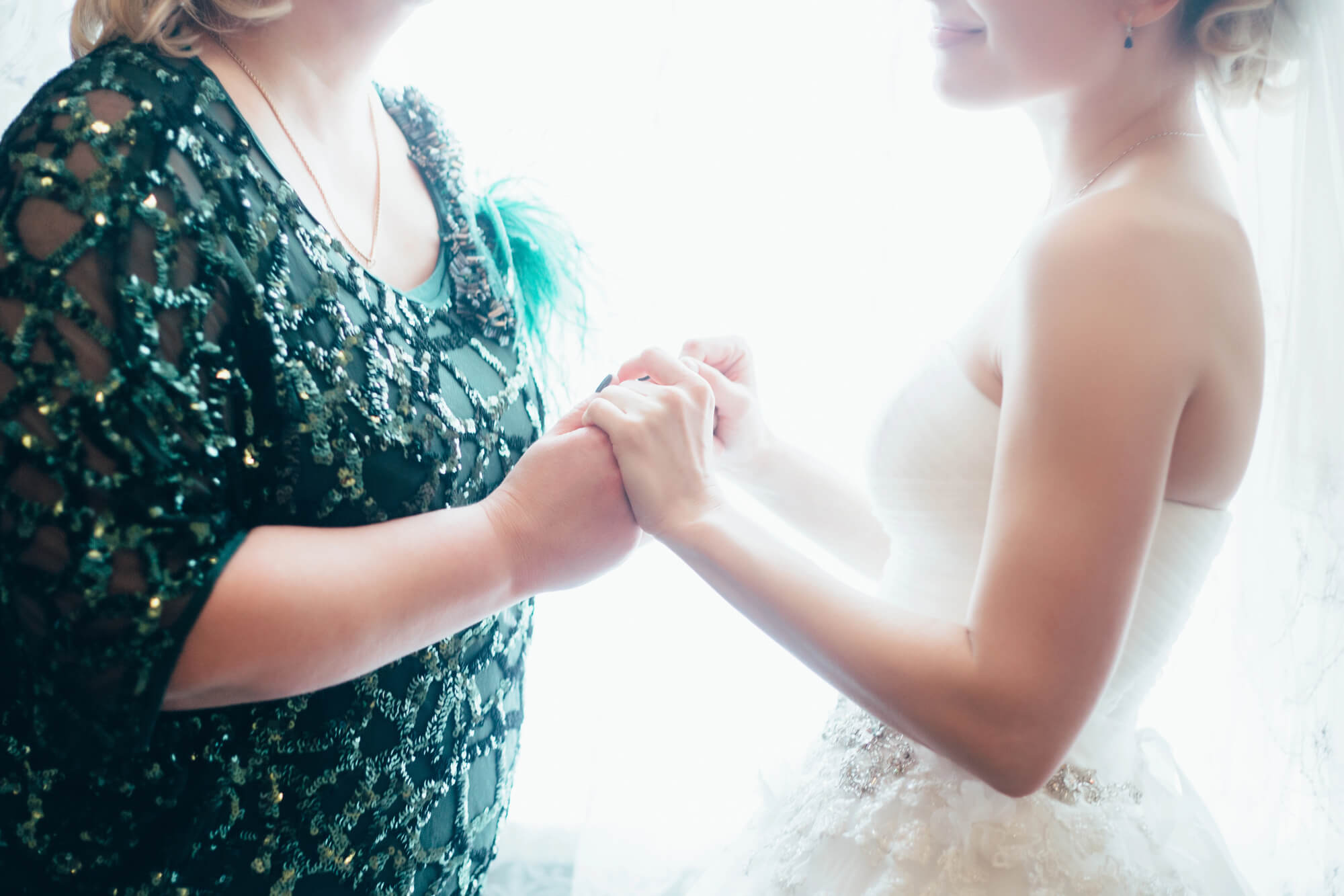 the bride in her wedding dress is holding hands with her mother before she gets married